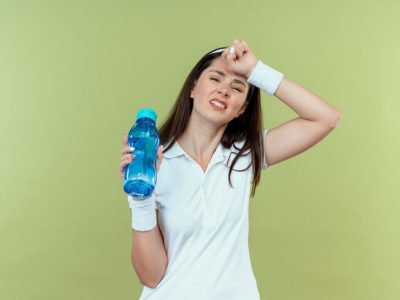 young-fitness-woman-headband-holding-bottle-water-looking-confused-displeased-standing-light-background_141793-67799